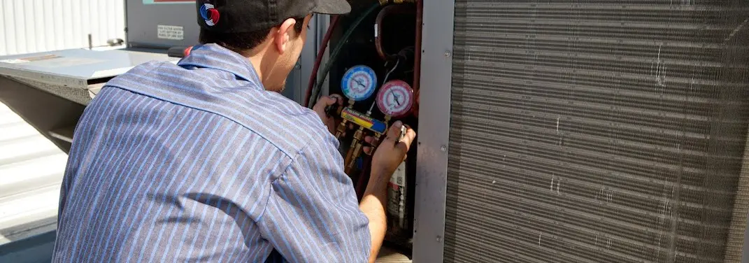 HVAC technician servicing a condenser unit in Sienna